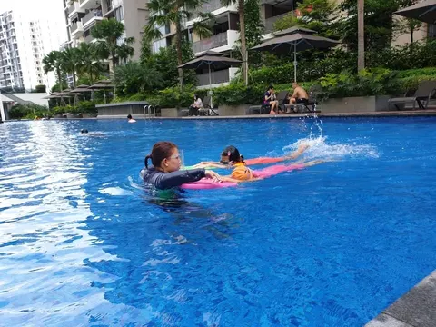 Coach Jina in the water guiding a young girl kicking on a pink float