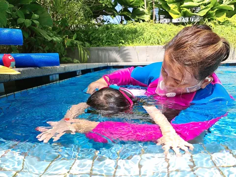 Coach Jina supporting a child practising a face-in-water float